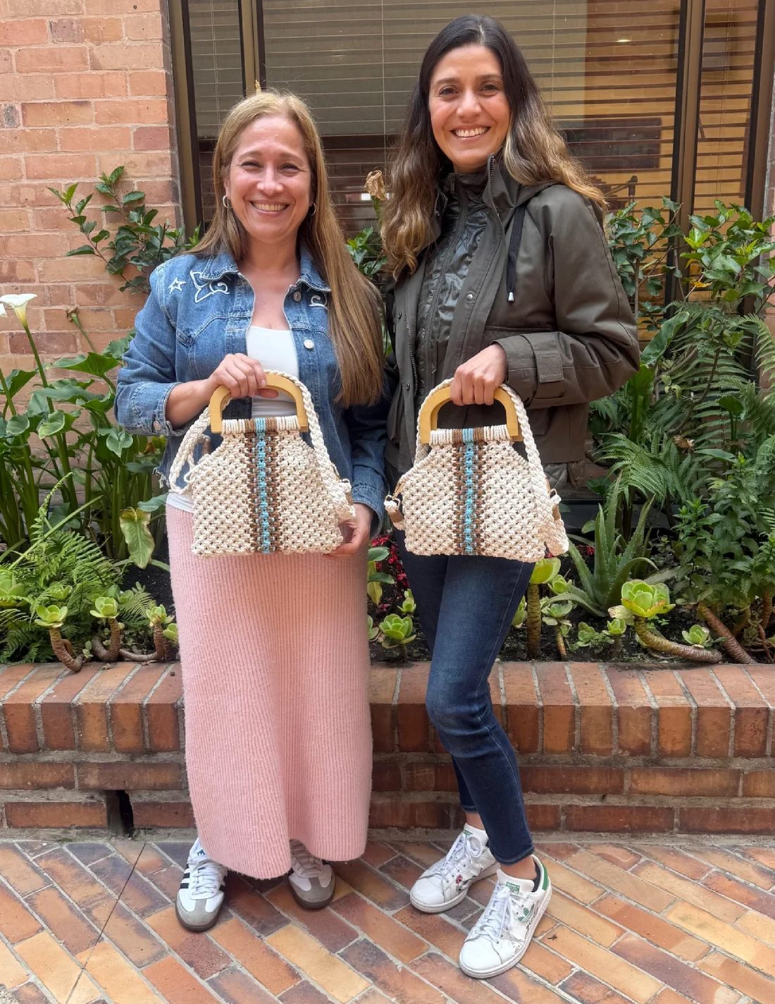 Dos estudiantes mostrando sus bolsos de macramé terminados