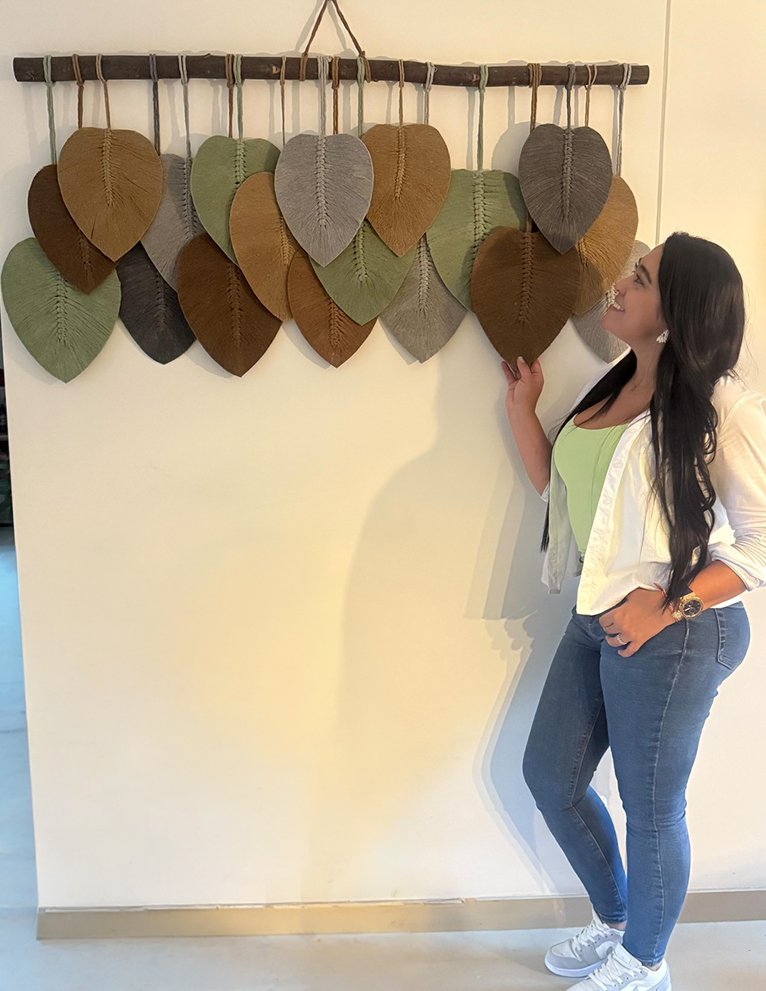 Estudiante junto a su tapiz de hojas de macramé